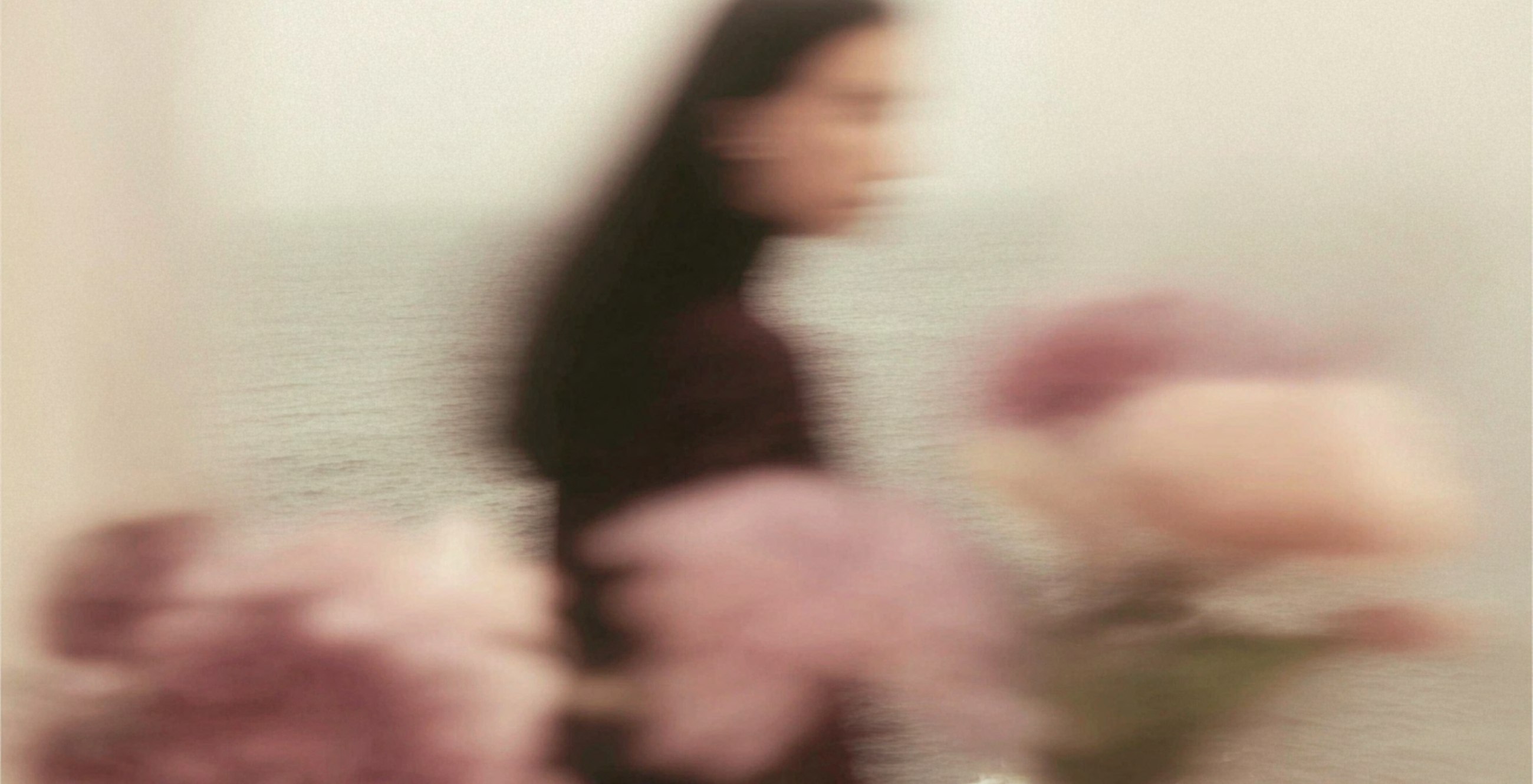 Soft-focus editorial portrait with flowers and sea in the background.