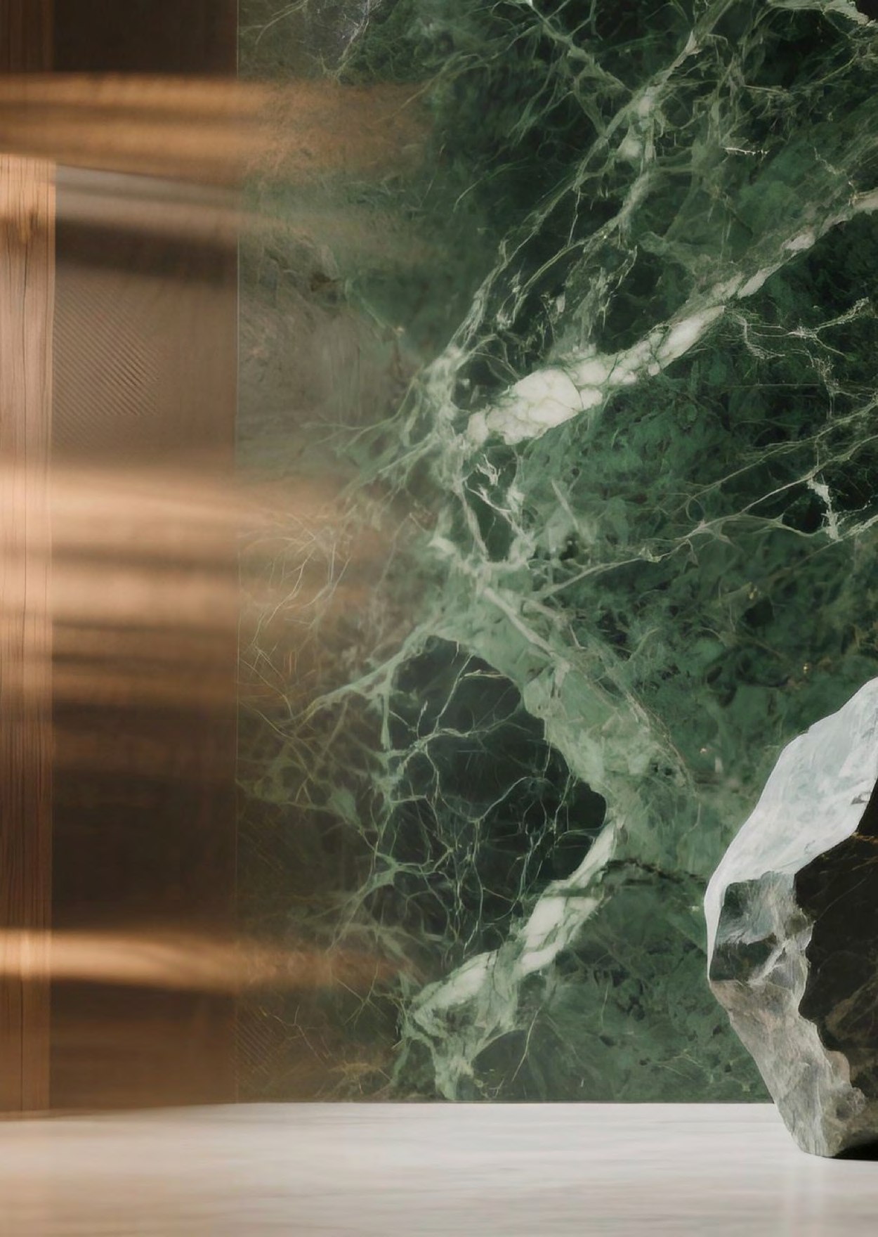 Close-up of green marble and warm metallic kitchen details.