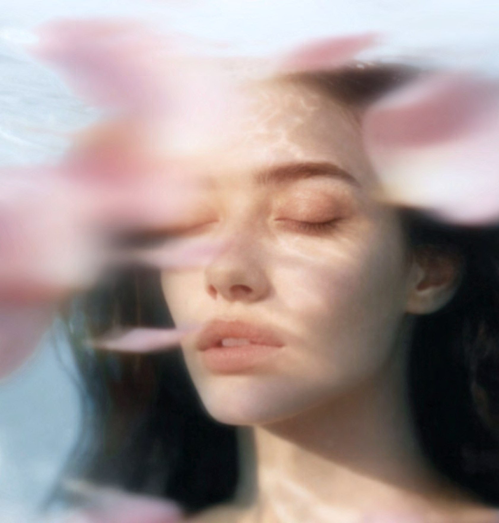 Editorial portrait seen through soft pink floral reflections.