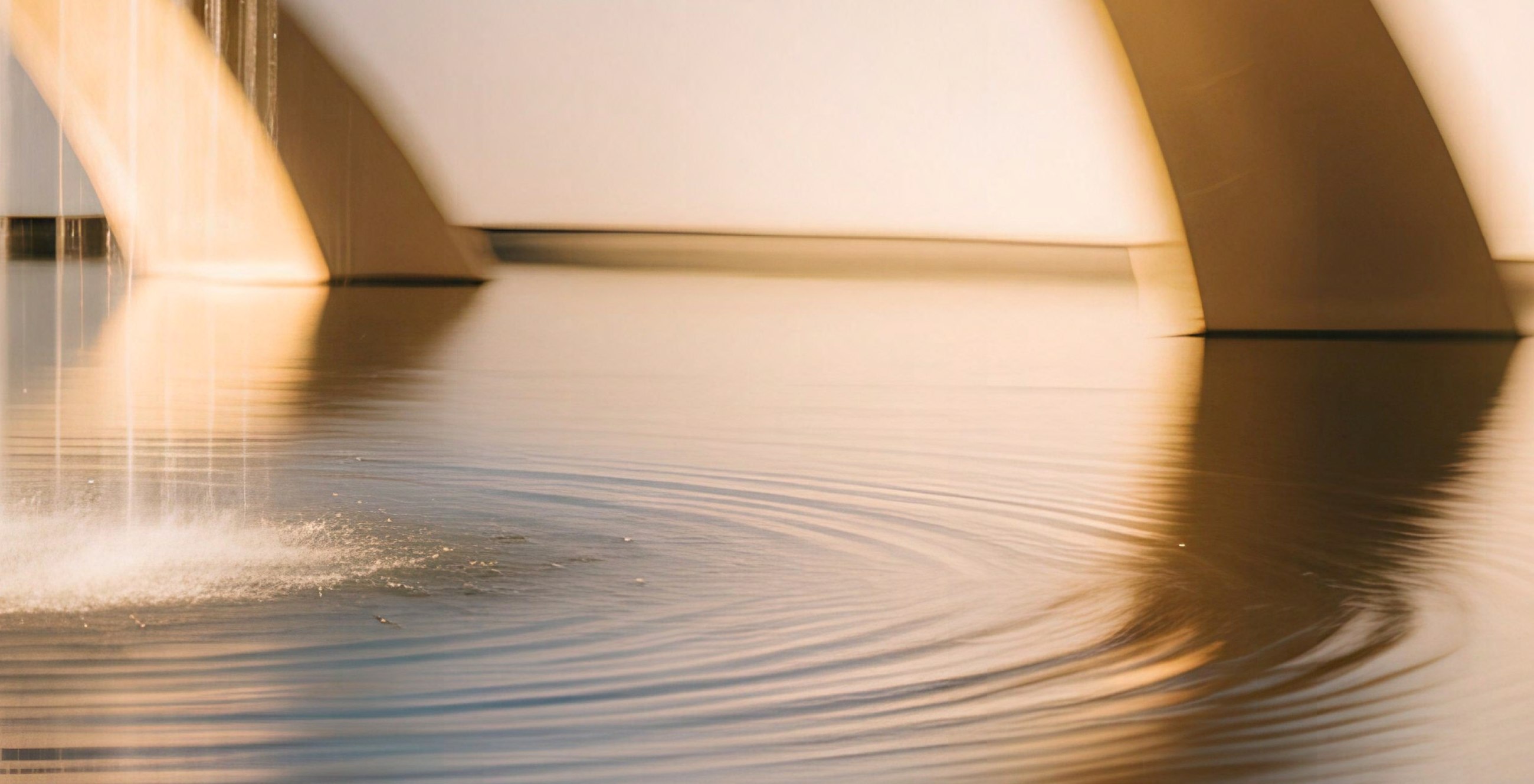 Warm architectural reflections and circular ripples on water.