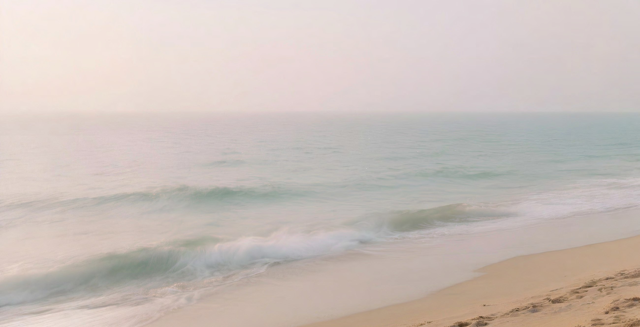 Quiet pastel beach and sea horizon with gentle waves.